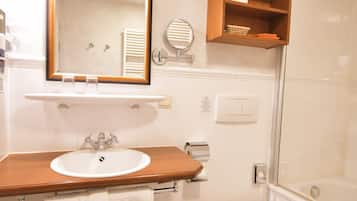 Ein Badezimmer mit einem hölzernen Waschtisch, einem weißen Waschbecken, einem beleuchteten Spiegel, einer Toilette und einem Schachbrettboden.