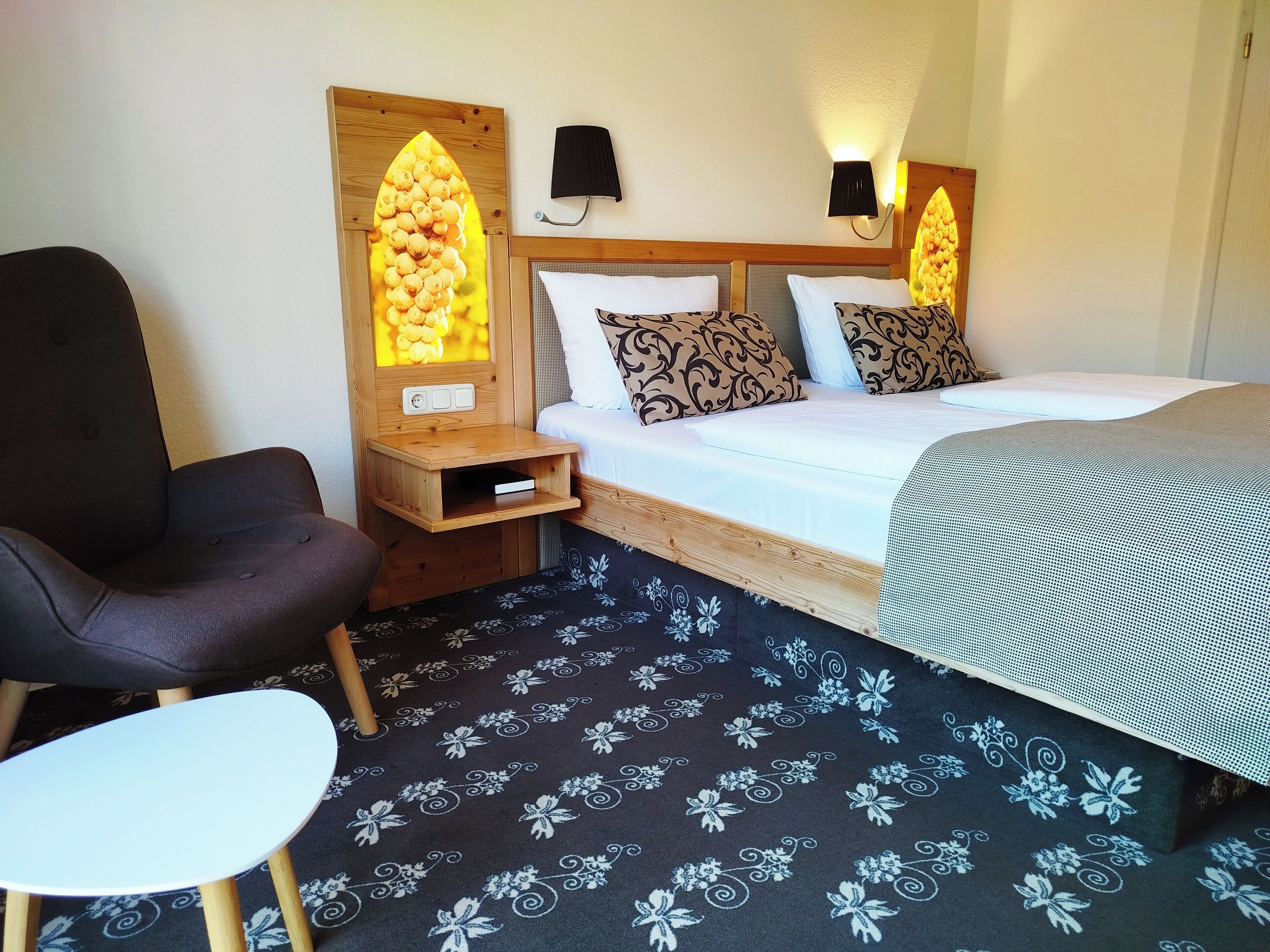 Ein Hotelzimmer mit einem Bett, einem Sessel, einem Nachttisch und zwei Wandlampen.