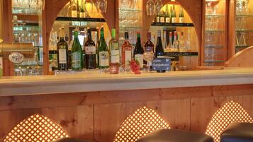 A bar area with wooden walls, shelves of wine bottles, and glasses.