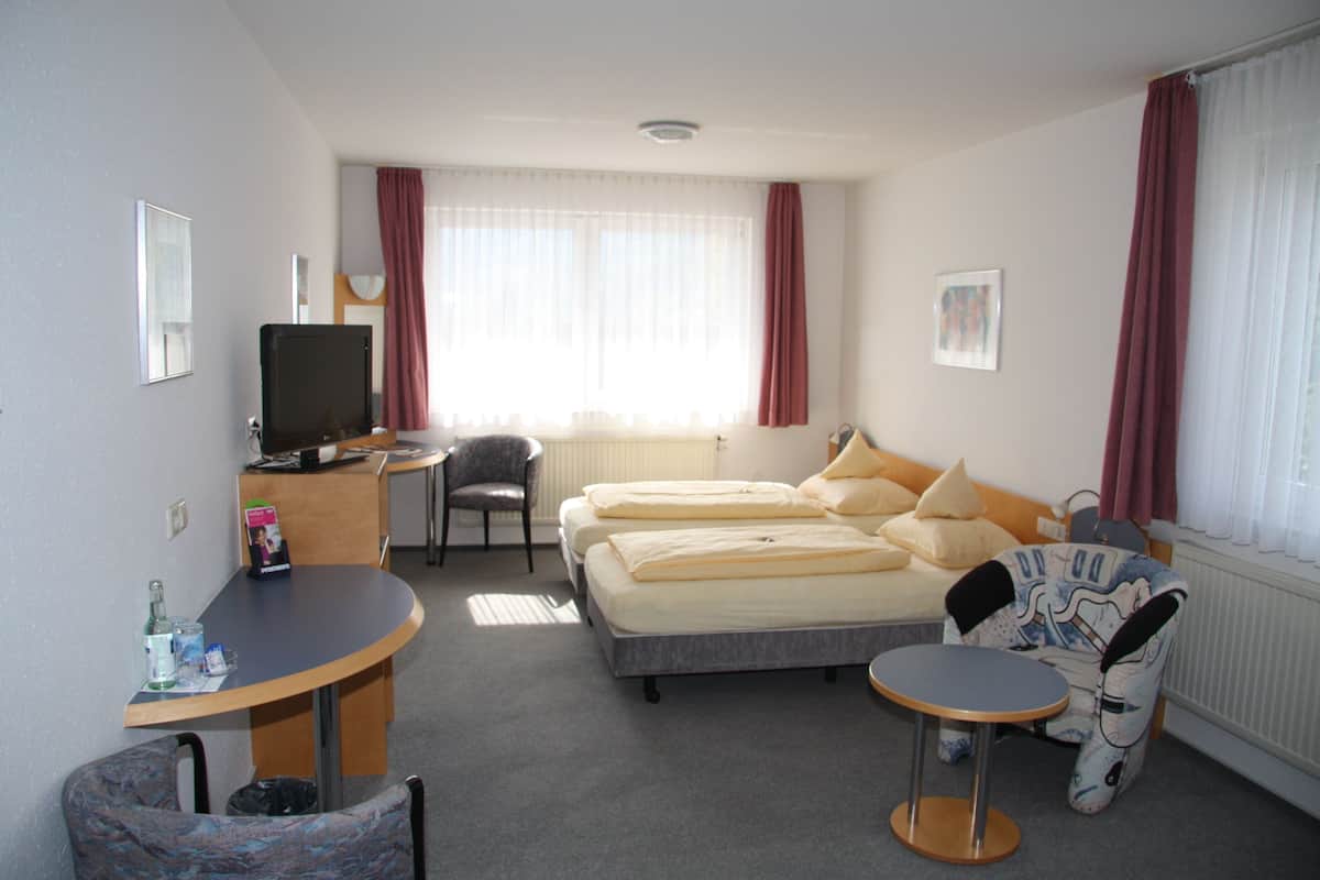 Een hotelkamer met een bed, bureau met computer, stoel, klein tafeltje en televisie.
