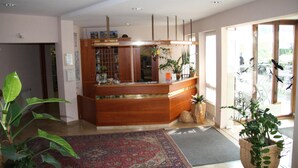A reception area with a wooden counter, potted plants, and a large window.