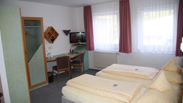 Ein Hotelzimmer mit zwei Betten, einem Schreibtisch, einem Stuhl, einem Fernseher und einem Kleiderschrank.