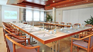 A conference room with a long table, chairs, and a projector screen.