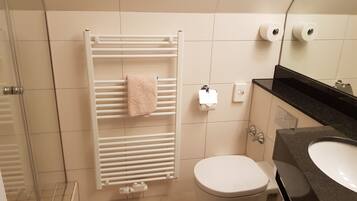 Un baño con radiador blanco, inodoro y lavabo.