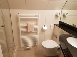 Un baño con radiador blanco, inodoro y lavabo.