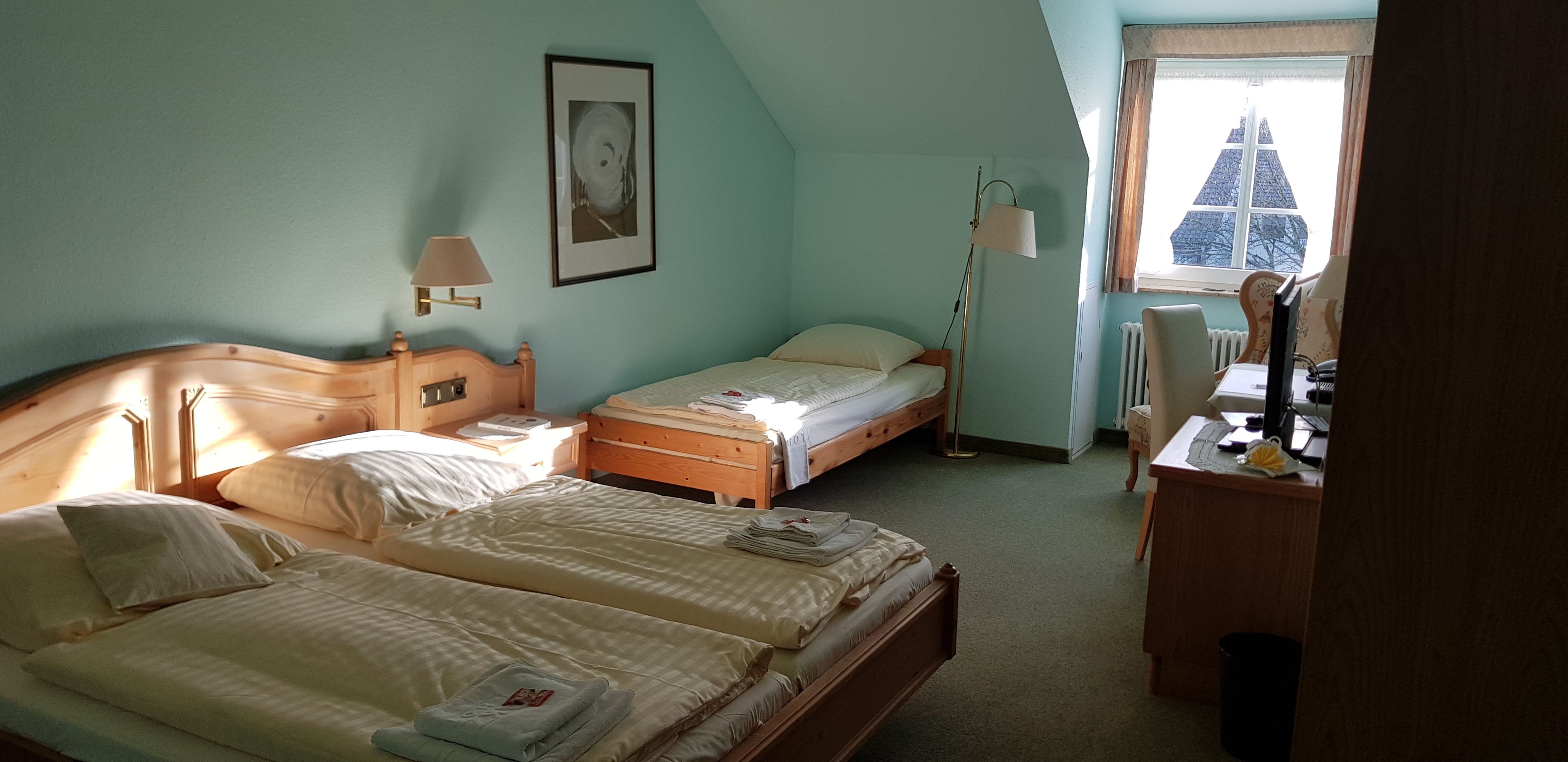 Camera da letto con due letti, una scrivania, una sedia, una lampada e una finestra vista edificio.