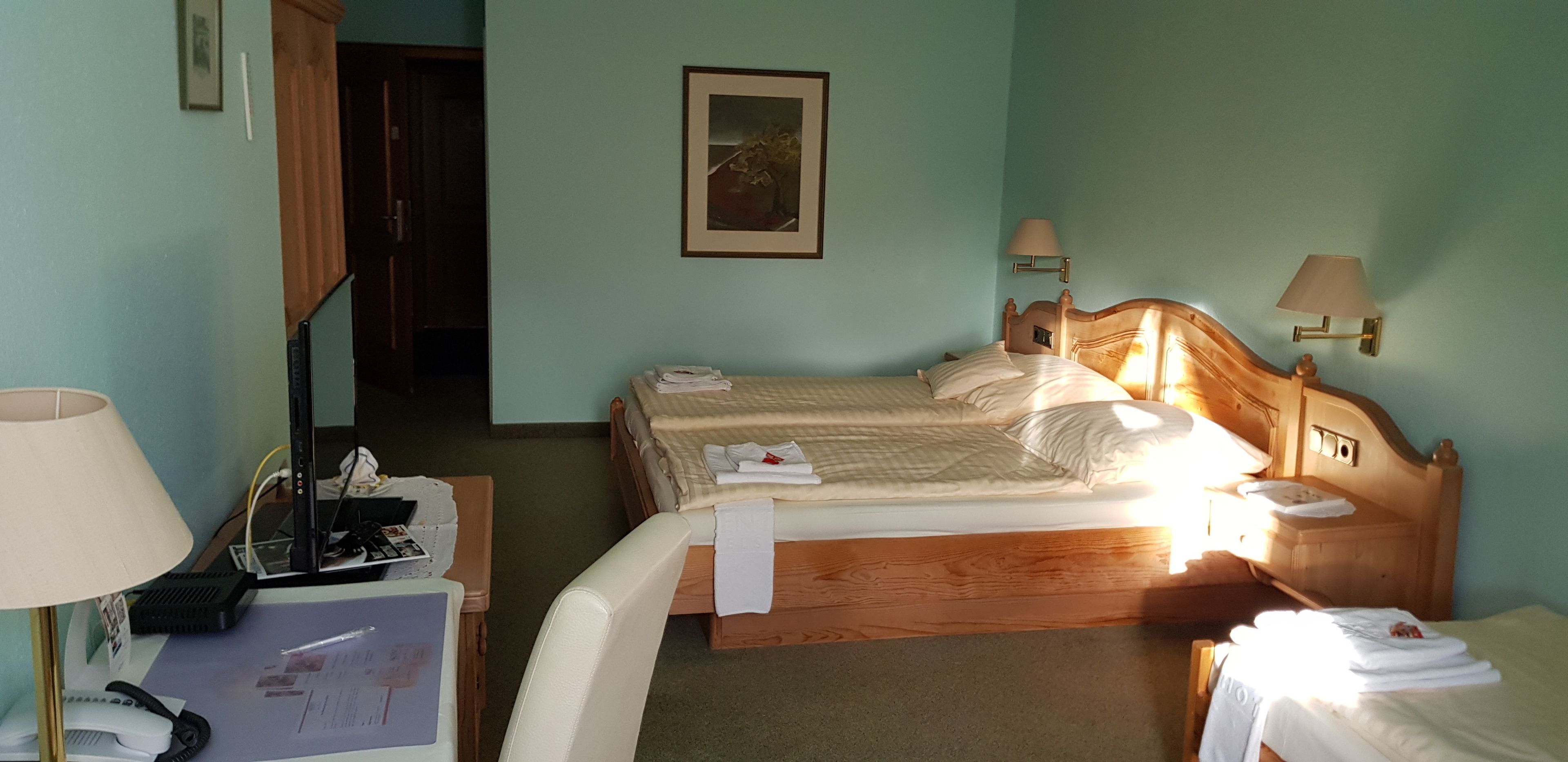 Habitación de hotel con cama, lámparas de noche, un escritorio con teléfono y una silla.