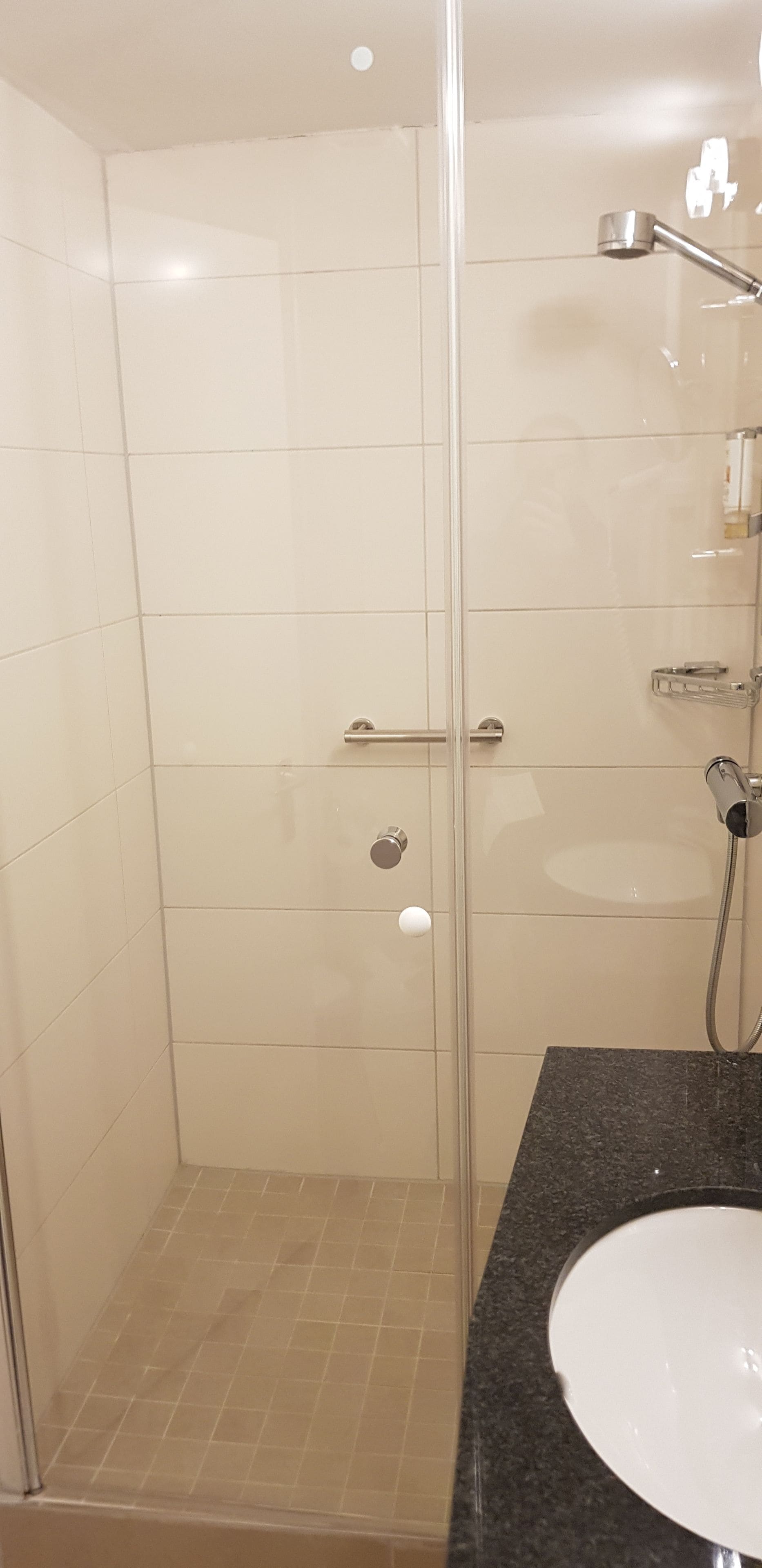 Un baño con cabina de ducha de vidrio, un lavabo y un espejo.