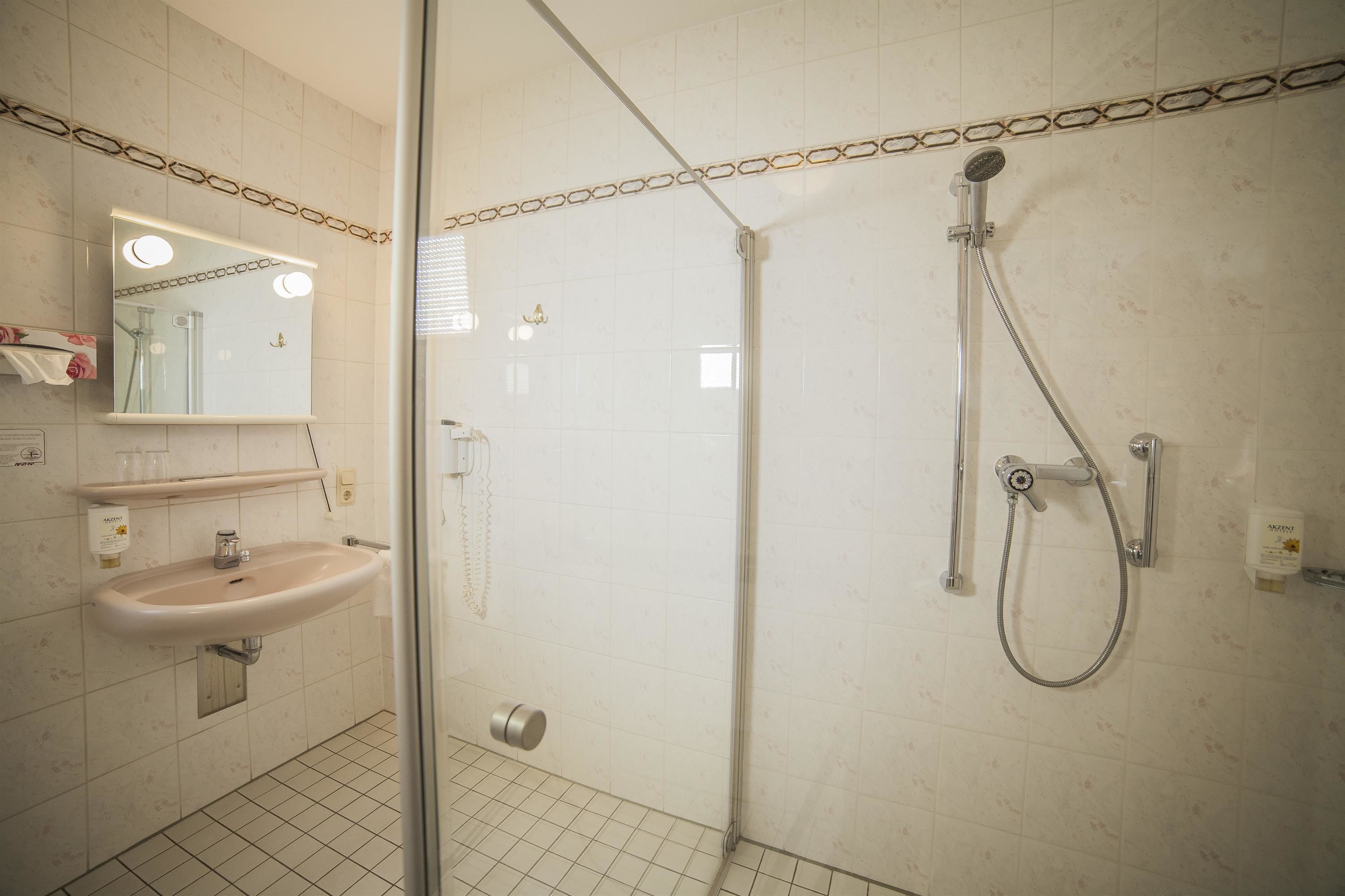 A bathroom with a sink, mirror, and shower.