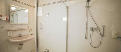 A bathroom with a sink, mirror, and shower.