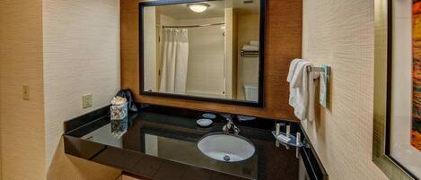 Un baño moderno con un lavabo negro, un espejo y una cortina de ducha.