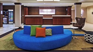 A modern lobby with a blue circular seating area, a reception desk, and a vending machine. - Fairfield Inn and Suites by Marriott Austin Northwest/Domain (Austin)