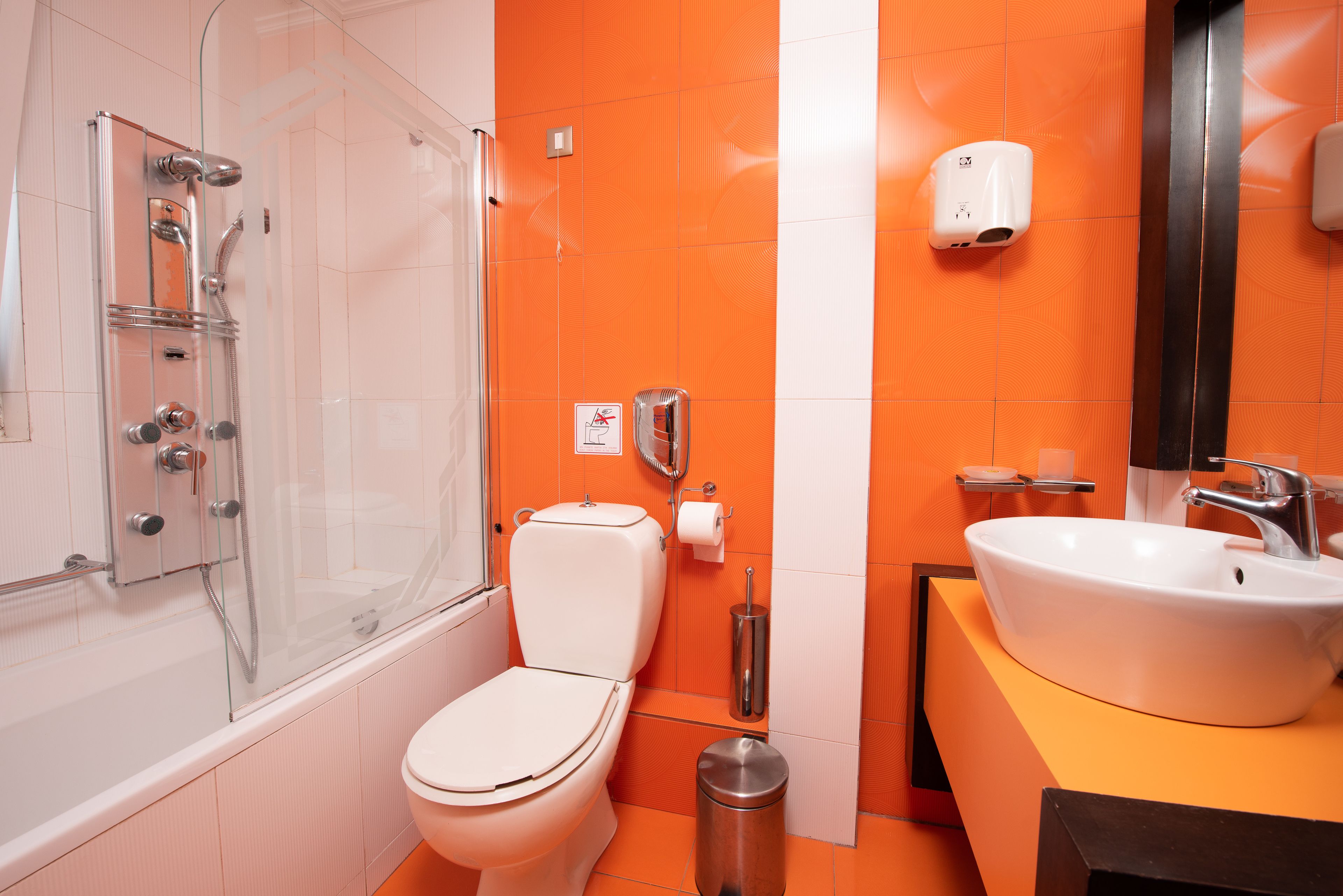 Un baño con ducha de vidrio, inodoro blanco y lavamanos con espejo.