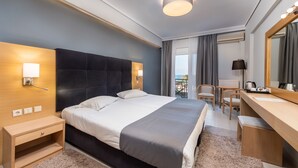 A modern hotel room with a large bed, bedside table, desk, and chair. - Heliotrope Hotels (Lesvos)