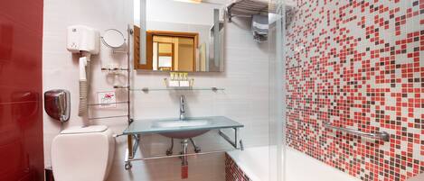 A bathroom with a glass sink, white toilet, and red-tiled floor.