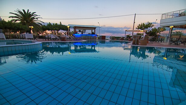 A swimming pool with tiled flooring, lounge chairs, and a bar area. - Heliotrope Hotels (Lesvos)
