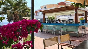An outdoor bar area with a pool view, wooden deck, and bar stools. - Heliotrope Hotels (Lesvos)