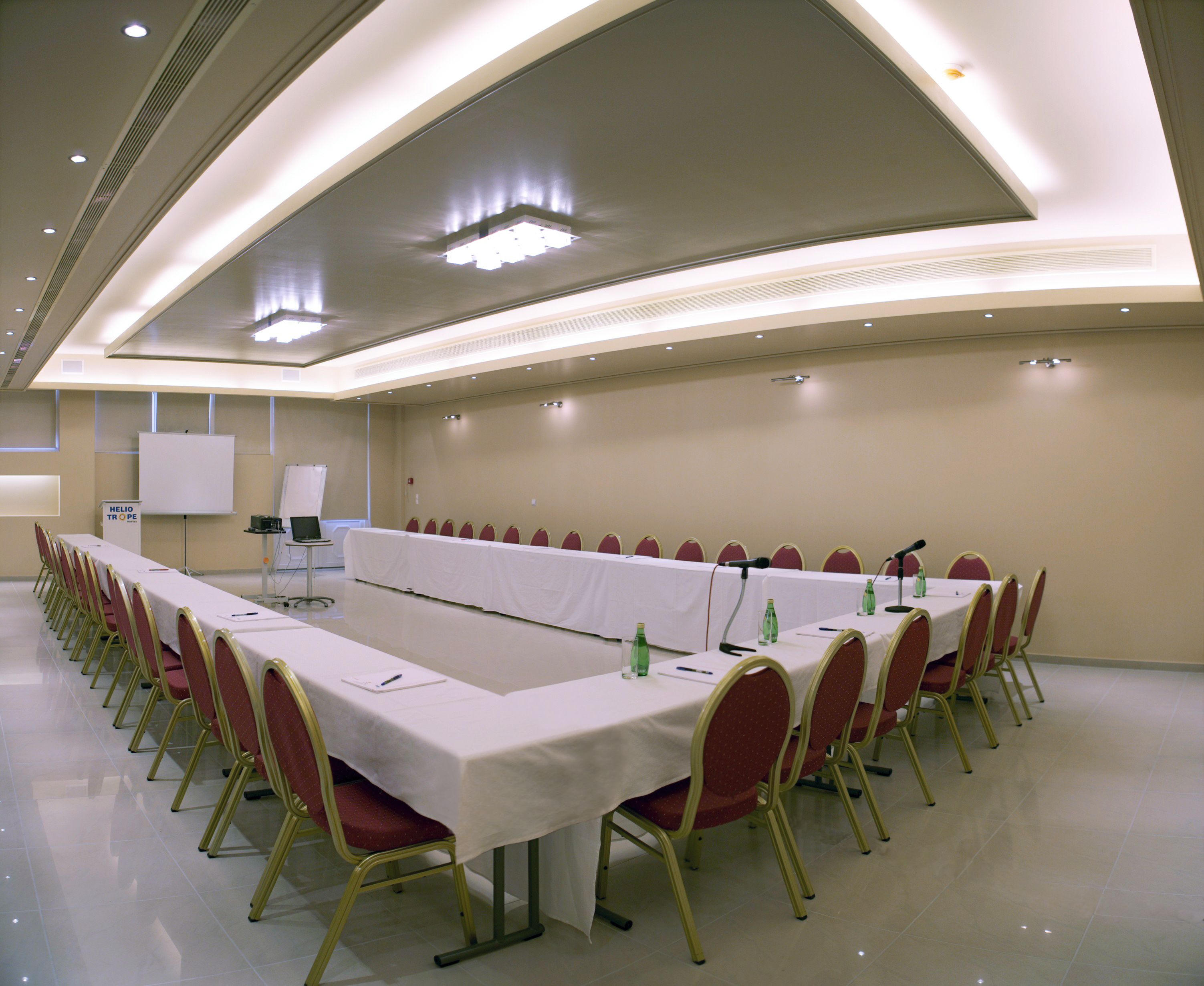 A conference room with a long table, red chairs, and a whiteboard.