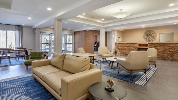 A spacious lobby with a beige sofa, a coffee machine, and a stone accent wall. - Fairfield Inn Suites by Marriott Cherokee (Cherokee)