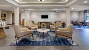 A spacious living area with a round coffee table, beige armchairs, and a modern ceiling light. - Fairfield Inn Suites by Marriott Cherokee (Cherokee)