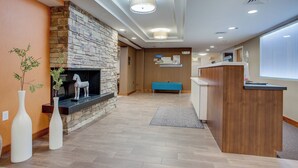 Eine moderne Hotelhalle mit Kamin aus Stein, einer Rezeption und einem blauen Sofa.