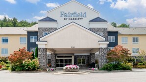 Eingang eines Fairfield by Marriott Hotels mit Stein-Fassade, großen Eingangstüren und einer bepflanzten Grünfläche mit Blumen.