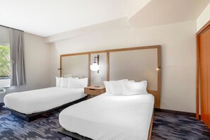 Quarto de hotel com duas camas, uma mesa de cabeceira, um espelho e uma janela com cortinas.
