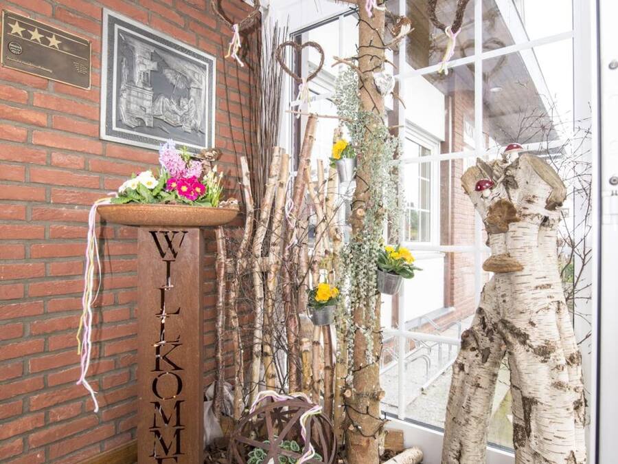 Un interior rústico con pared de ladrillo, un letrero de madera y elementos decorativos como ramas y flores.