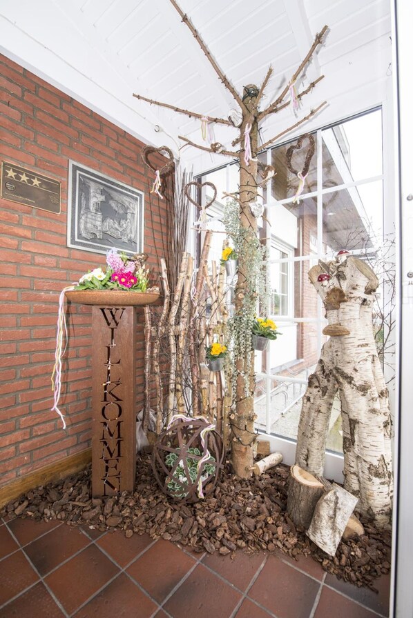 Un intérieur rustique avec un mur en briques, une enseigne en bois et des éléments décoratifs tels que des branches et des fleurs.
