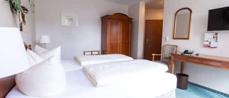 Une chambre d’hôtel comprenant un lit, un bureau, une chaise, un miroir et un téléviseur.