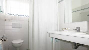 A bathroom with a toilet, a sink, a mirror, and a shower curtain.