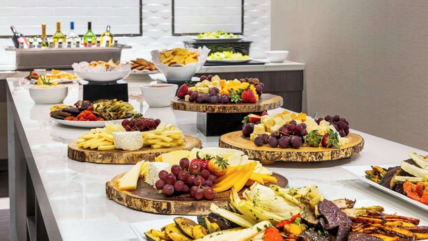 Una mesa de buffet con varios quesos, frutas y verduras.