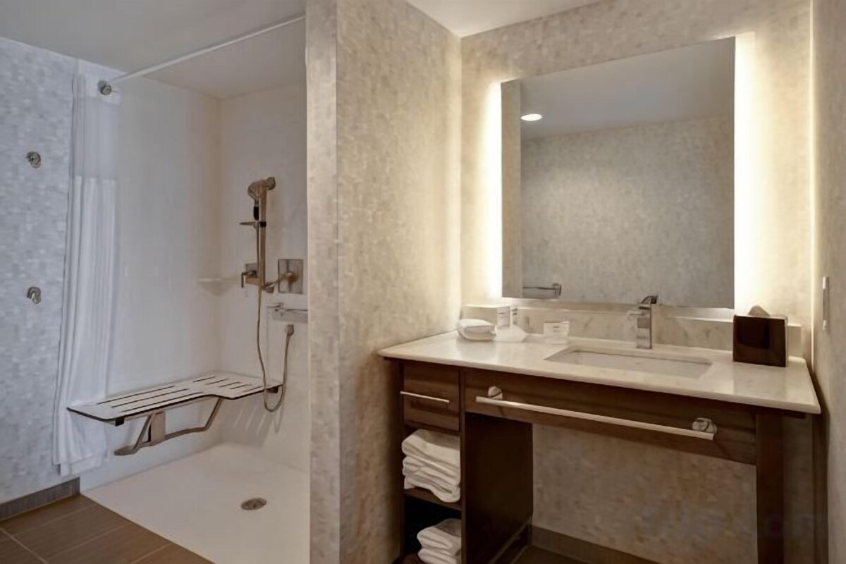 Une salle de bain avec une douche, un lavabo et un miroir.