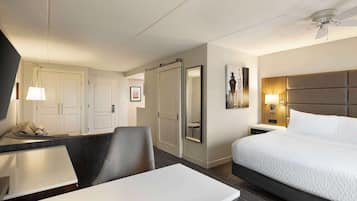 Une chambre d’hôtel équipée d’un lit, d’un bureau, d’une chaise, d’une armoire et d’un ventilateur de plafond.