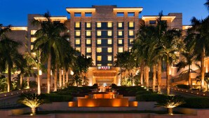 Un hotel Hyatt con una entrada bien iluminada, palmeras y una fuente central.