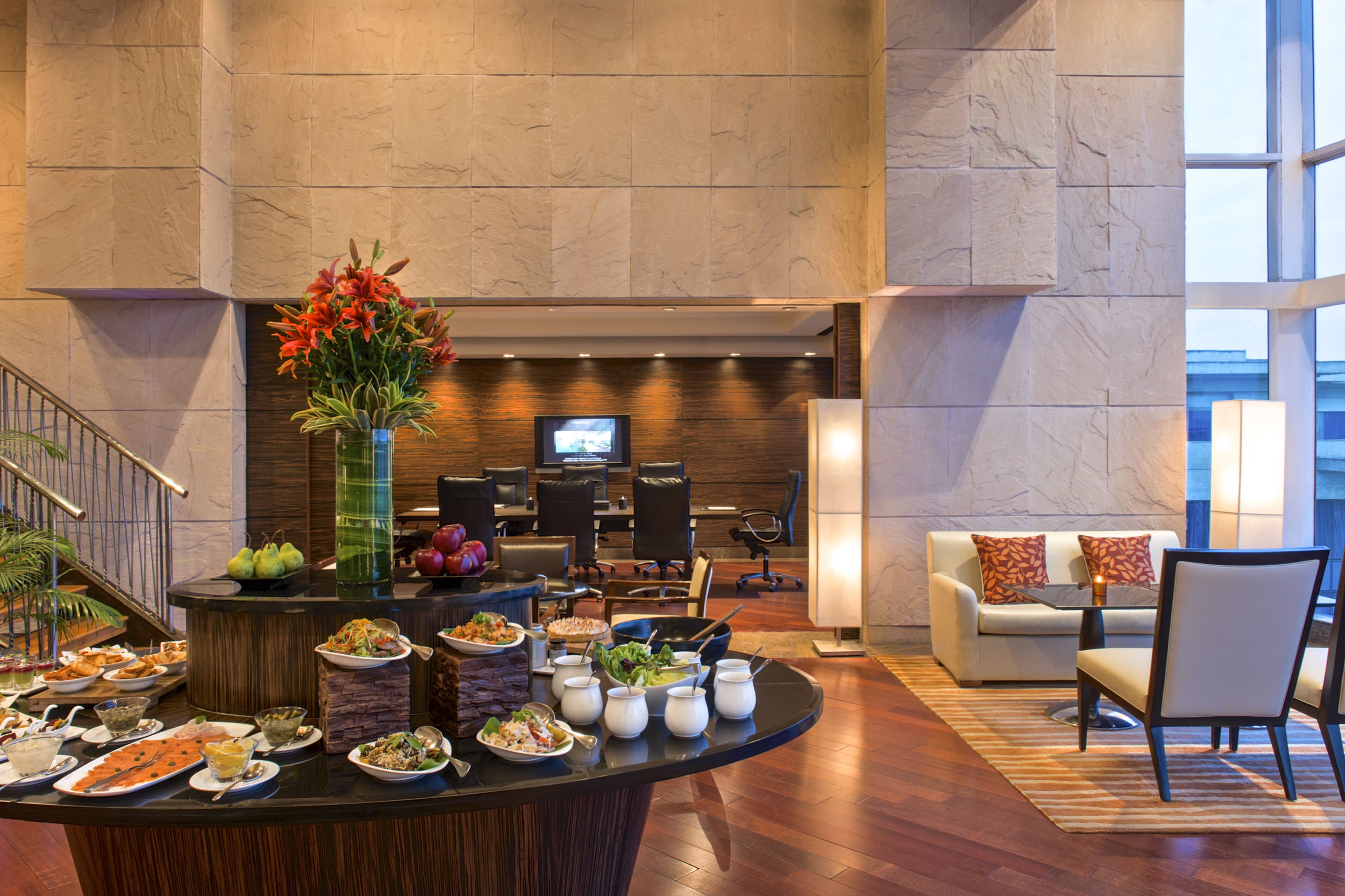 A hotel lobby with a buffet, seating area, and a television.