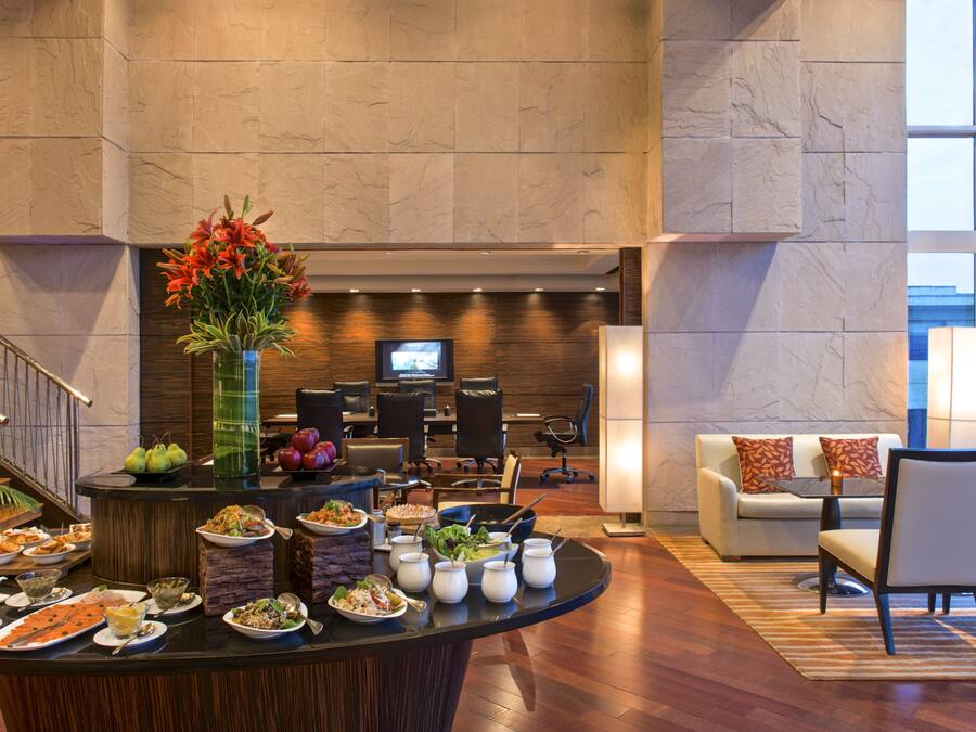 A hotel lobby with a buffet, seating area, and a television.