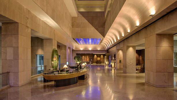 Un vestíbulo amplio con una recepción, zona de estar y una gran pieza decorativa central.
