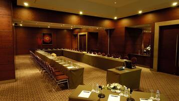 A conference room with long tables, chairs, and a podium.