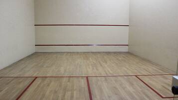 A squash court with wooden flooring and red boundary lines.