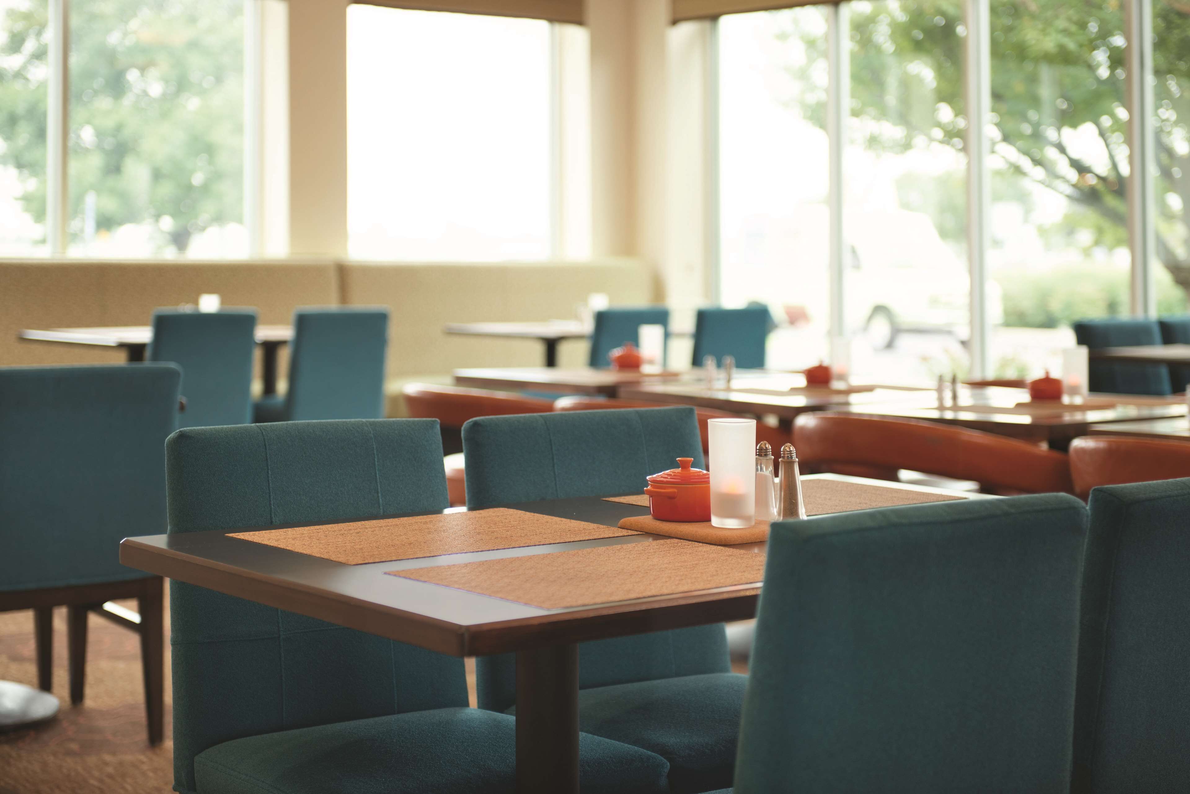 A restaurant with tables and chairs, large windows, and a view of the outdoors.