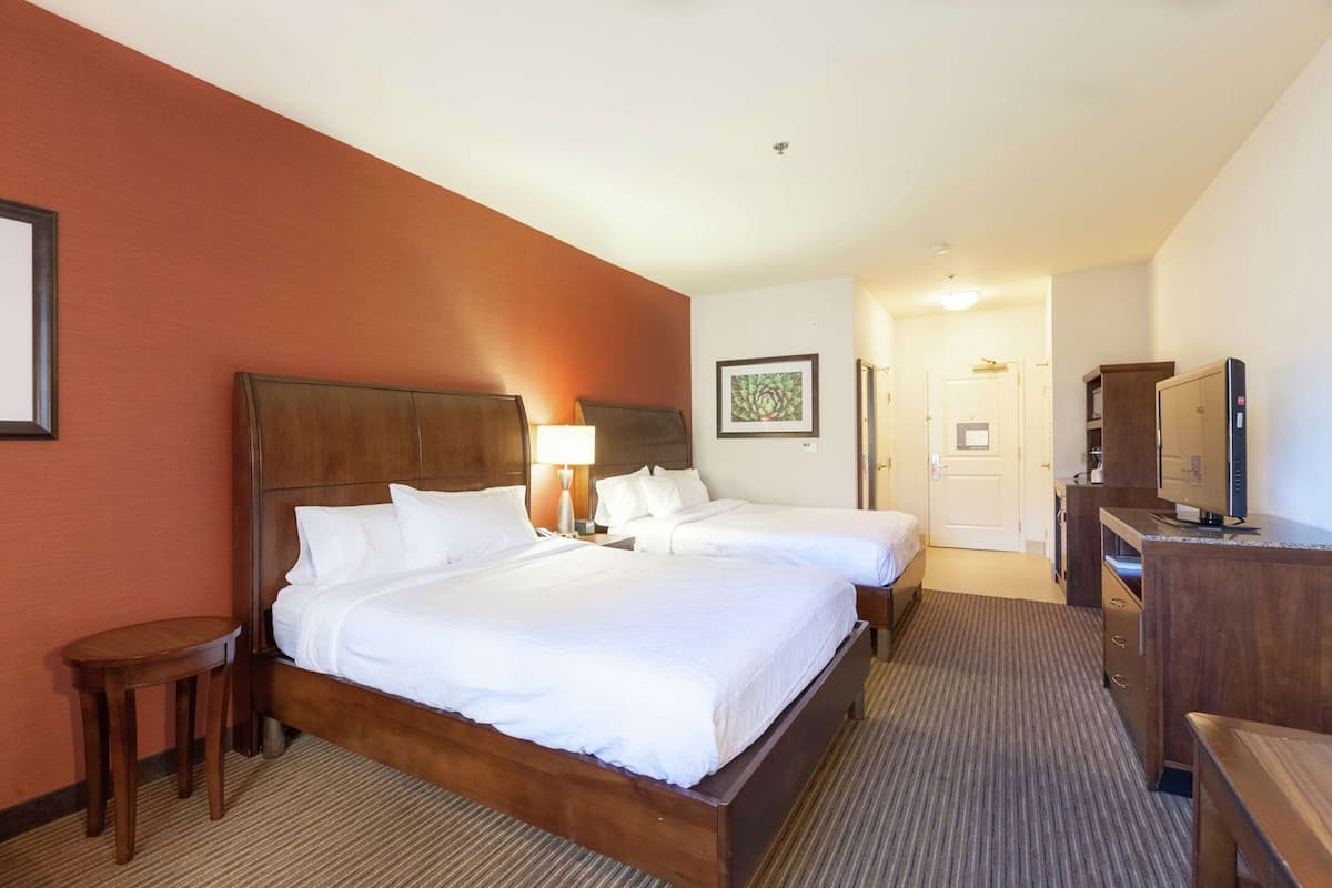 A hotel room with a large bed, a desk with a computer, a lamp, and a framed picture on the wall.