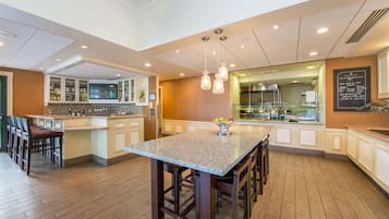 A modern kitchen with a central island, bar seating, and a large window overlooking the dining area.