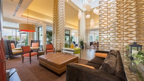 A spacious lobby with high ceilings, modern furniture, and large windows offering views of the outdoors.