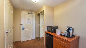 Habitación de hotel con una kitchenette compacta, que incluye microondas, cafetera y un refrigerador pequeño.