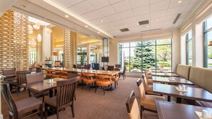 A spacious hotel lobby with multiple seating areas, large windows offering views of the outdoors, and a modern interior design.