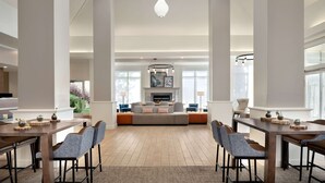 Un vaste espace de vie comprenant un grand canapé, une table à manger et des chaises, une cheminée et une vue sur l’extérieur.