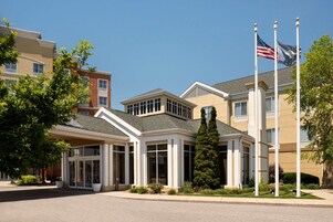 A hotel with a modern entrance, large windows, and a flagpole with the American flag.