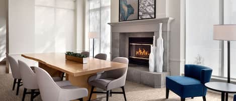 Un comedor moderno con una mesa y sillas de madera, una chimenea y ventanas grandes.