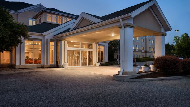Une entrée d’hôtel moderne, dotée d’une allée couverte et de grandes fenêtres.